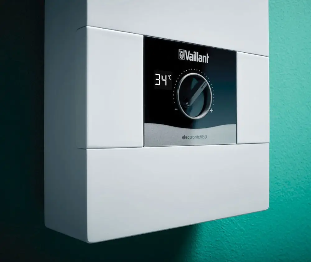 Vaillant Elektro-Durchlauferhitzer mit digitaler Anzeige und Temperaturregler an einer wandfarbenen Fläche. Display zeigt eine Temperatur von 34°C.